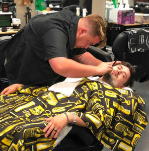 Dustin is giving customer a face shave using straight razor and shaving soap.